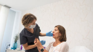 Una doctora especializada en medicina estética revisando a una paciente tras el tratamiento de rejuvenecimiento facial realizado.